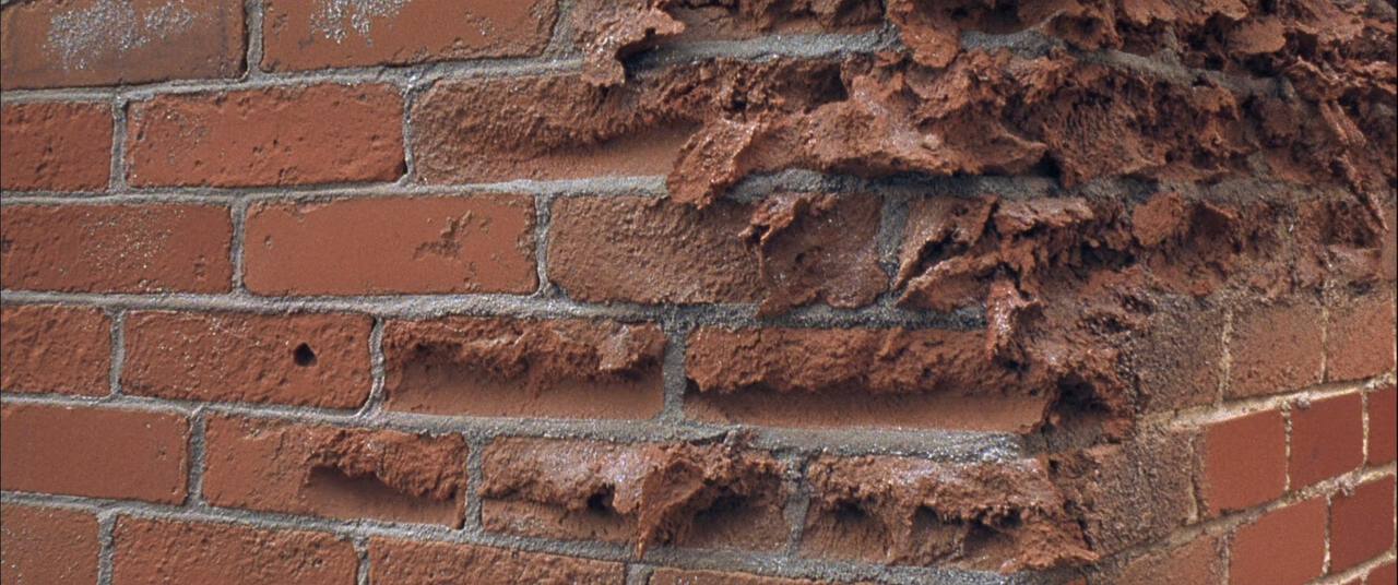 Close-up of a brick chimney with spalled brick faces and eroded mortar joints